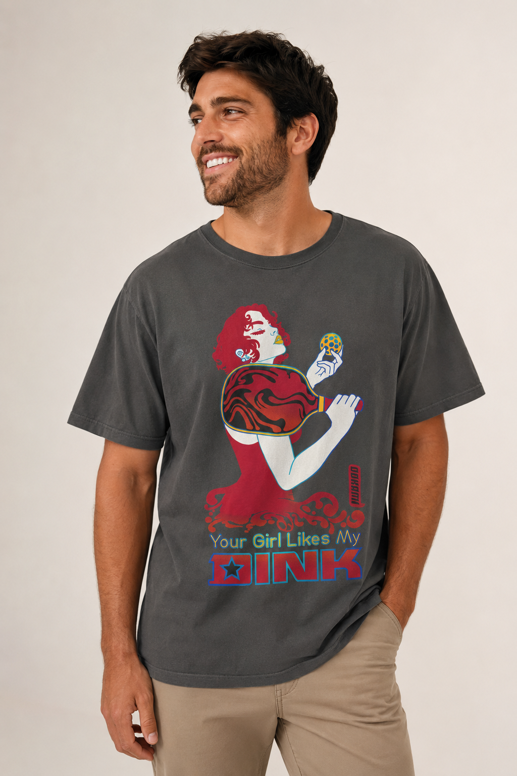 Smiling male model wearing a charcoal gray Your Girl Likes My Dink funny pickleball graphic T-shirt