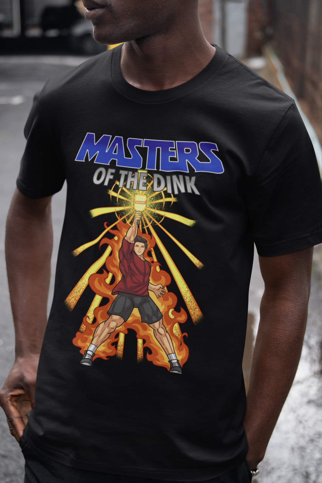 Man wearing a black Masters of the Dink pickleball graphic T-shirt with fiery retro artwork.
